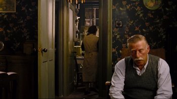 Movie still from “Vera Drake” (2004), directed by Mike Leigh – A man sitting in a chair in front of a woman; Medium shot, Over the shoulder angle