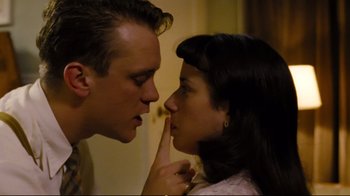 Movie still from “Vera Drake” (2004), directed by Mike Leigh – A man and a woman face to face with one of them holding a finger up to their lips; Close Up shot, High angle
