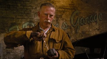 Movie still from “Vera Drake” (2004), directed by Mike Leigh – An older man wearing a brown jacket holding a brown object; Close Up shot, Low angle