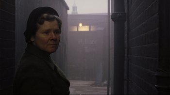 Movie still from “Vera Drake” (2004), directed by Mike Leigh – An older woman standing in the middle of an alleyway; Close Up shot, Low angle