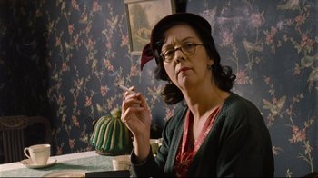 Movie still from “Vera Drake” (2004), directed by Mike Leigh – A woman sitting at a table with a cigarette in her mouth; Close Up shot, Low angle