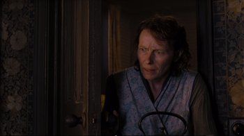 Movie still from “Vera Drake” (2004), directed by Mike Leigh – An older woman standing next to a door looking at the camera; Medium shot, Low angle