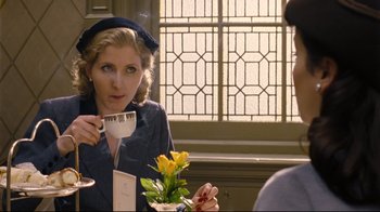 Movie still from “Vera Drake” (2004), directed by Mike Leigh – A woman sitting at a table holding a coffee cup; Medium shot, Over the shoulder angle