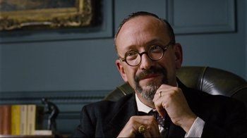 Movie still from “Vera Drake” (2004), directed by Mike Leigh – A man in a suit and tie with a beard and glasses; Close Up shot, Low angle