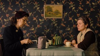 Movie still from “Vera Drake” (2004), directed by Mike Leigh – Two people sitting at a table with a tea pot and cups; Medium shot, High angle