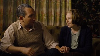 Movie still from “Vera Drake” (2004), directed by Mike Leigh – A man and a woman sitting on a couch talking to each other; Medium shot, High angle