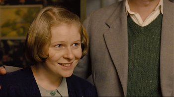 Movie still from “Vera Drake” (2004), directed by Mike Leigh – A young woman smiles while standing next to an older man; Close Up shot, Over the shoulder angle