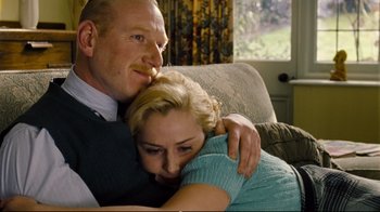 Movie still from “Vera Drake” (2004), directed by Mike Leigh – A man and a woman hugging on a couch; Close Up shot, Over the shoulder angle