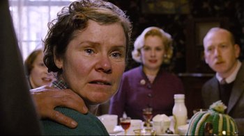 Movie still from “Vera Drake” (2004), directed by Mike Leigh – Two women sitting at a dinner table , one of whom has her hand on the shoulder of another woman; Close Up shot, Over the shoulder angle