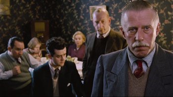 Movie still from “Vera Drake” (2004), directed by Mike Leigh – A group of people sitting around a table; Medium shot, Low angle