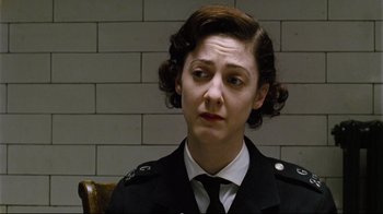 Movie still from “Vera Drake” (2004), directed by Mike Leigh – A woman in a uniform sitting in front of a brick wall; Close Up shot, Low angle