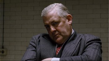 Movie still from “Vera Drake” (2004), directed by Mike Leigh – An older man in a gray suit and red neck tie; Close Up shot, Low angle