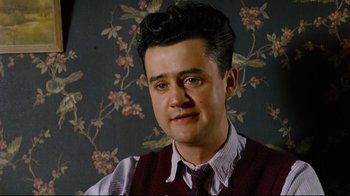 Movie still from “Vera Drake” (2004), directed by Mike Leigh – A man in a vest and a tie is posing for a picture; Close Up shot, Low angle