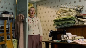 Movie still from “Vera Drake” (2004), directed by Mike Leigh – A woman standing in front of a sewing machine; Medium shot, Low angle