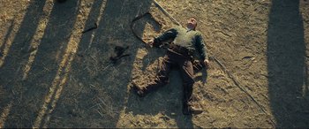 Movie still from “Vice” (2018), directed by Adam McKay – A man laying on the ground in the dirt; Wide shot, Overhead angle