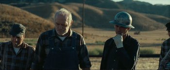 Movie still from “Vice” (2018), directed by Adam McKay – Two men standing next to each other on a dirt field; Medium shot, Low angle
