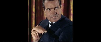 Movie still from “Vice” (2018), directed by Adam McKay – An older man wearing a suit and tie with a watch; Close Up shot, Low angle