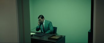 Movie still from “Vice” (2018), directed by Adam McKay – A man sitting at a desk talking on a phone; Wide shot, High angle