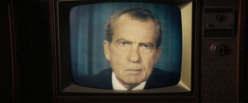 Movie still from “Vice” (2018), directed by Adam McKay – An older man in a suit and tie on a television screen; Extreme Close Up shot, Low angle