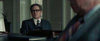 Movie still from “Vice” (2018), directed by Adam McKay – A man wearing a suit and tie sitting in front of a table; Close Up shot, Over the shoulder angle