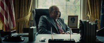 Movie still from “Vice” (2018), directed by Adam McKay – An older man sitting at a desk in front of a window; Medium shot, Low angle