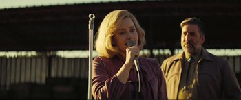 Movie still from “Vice” (2018), directed by Adam McKay – A woman with blonde hair is holding a microphone; Close Up shot, Over the shoulder angle