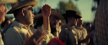 Movie still from “Vice” (2018), directed by Adam McKay – A group of people in a crowd holding their hands up; Close Up shot, Low angle