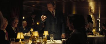 Movie still from “Vice” (2018), directed by Adam McKay – A man in a suit is holding a glass of wine; Medium shot, Over the shoulder angle