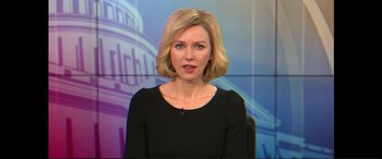 Movie still from “Vice” (2018), directed by Adam McKay – A woman in a black shirt is standing in front of a tv; Close Up shot, Over the shoulder angle