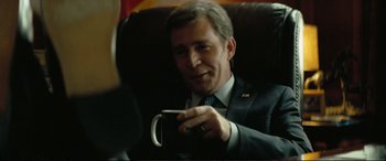 Movie still from “Vice” (2018), directed by Adam McKay – A man sitting in a chair holding a mug; Close Up shot, Over the shoulder angle