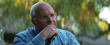 Movie still from “Vice” (2018), directed by Adam McKay – An older man wearing glasses and a plaid shirt; Close Up shot, Over the shoulder angle