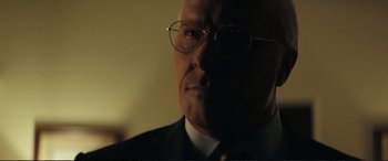 Movie still from “Vice” (2018), directed by Adam McKay – An older man wearing glasses and a suit; Close Up shot, Low angle