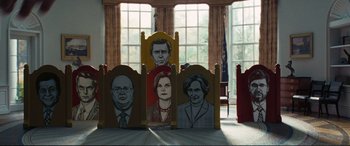 Movie still from “Vice” (2018), directed by Adam McKay – A group of four chairs with faces painted on them in front of a window; Wide shot, Low angle