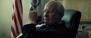 Movie still from “Vice” (2018), directed by Adam McKay – An older man wearing glasses and a suit and a watch; Close Up shot, Low angle