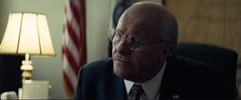Movie still from “Vice” (2018), directed by Adam McKay – An older man wearing glasses and a suit and tie; Close Up shot, Low angle