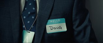 Movie still from “Vice” (2018), directed by Adam McKay – A name tag is attached to a suit jacket; Extreme Close Up shot, High angle
