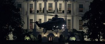 Movie still from “Vice” (2018), directed by Adam McKay – A helicopter flying over a building at night time; Extreme Wide shot, Low angle