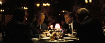 Movie still from “Vice” (2018), directed by Adam McKay – A couple of men sitting at a dinner table at a restaurant; Medium shot, Over the shoulder angle