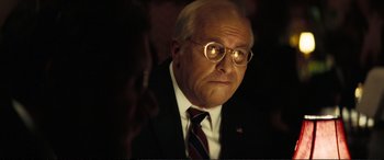 Movie still from “Vice” (2018), directed by Adam McKay – A man in a suit and tie with glasses on; Close Up shot, Over the shoulder angle