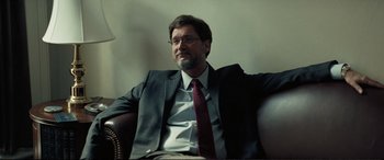 Movie still from “Vice” (2018), directed by Adam McKay – A man in a suit and tie sitting in a chair; Medium shot, Over the shoulder angle
