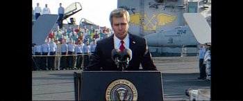 Movie still from “Vice” (2018), directed by Adam McKay – A man in a suit and tie standing at a podium with microphones; Medium shot, Low angle