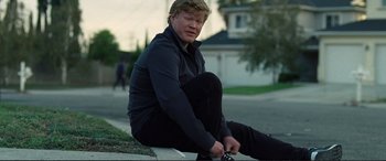 Movie still from “Vice” (2018), directed by Adam McKay – A man sitting on the side of the road tying his shoes; Medium shot, Low angle