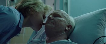 Movie still from “Vice” (2018), directed by Adam McKay – An older man laying in a hospital bed with a young woman; Close Up shot, Low angle