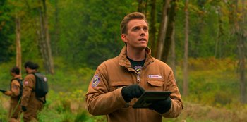 Movie still from “Another Life” (2019), created by Aaron Martin – A man in a brown jacket holding a tablet in his hands; Close Up shot, Over the shoulder angle
