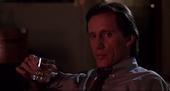 Movie still from “Videodrome” (1983), directed by David Cronenberg – A man holding a glass in his right hand; Close Up shot, Low angle