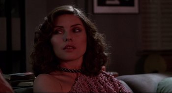 Movie still from “Videodrome” (1983), directed by David Cronenberg – A woman in a pink dress is sitting on a couch; Close Up shot, Over the shoulder angle