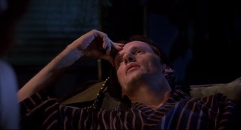 Movie still from “Videodrome” (1983), directed by David Cronenberg – A man is sitting in a chair with his hand to his head; Close Up shot, High angle