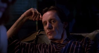 Movie still from “Videodrome” (1983), directed by David Cronenberg – A person sitting on a couch in a room; Close Up shot, Low angle