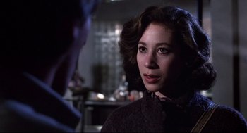 Movie still from “Videodrome” (1983), directed by David Cronenberg – A woman in a brown coat looking at a man in a black suit; Close Up shot, Over the shoulder angle
