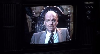 Movie still from “Videodrome” (1983), directed by David Cronenberg – A man in a suit and tie sitting in a chair; Close Up shot, Low angle